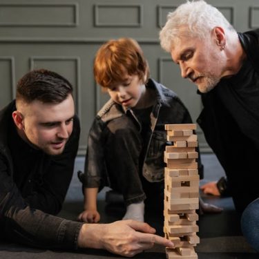 A joyful family scene with a grandparent, parent, and child enjoying a game of Jenga together.